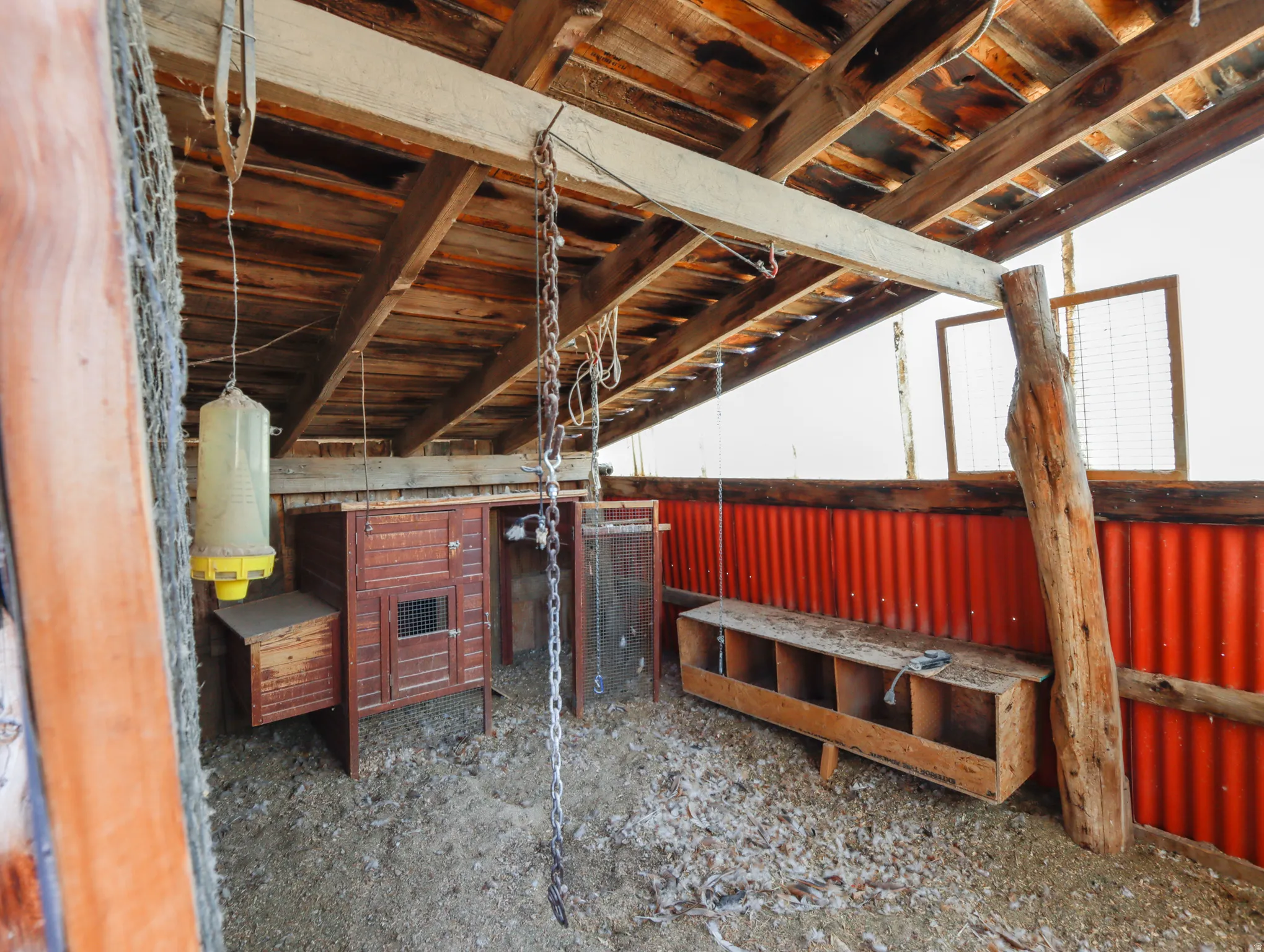 Open-air structure featuring exposed wood beams, a corrugated metal wall, and wooden support posts