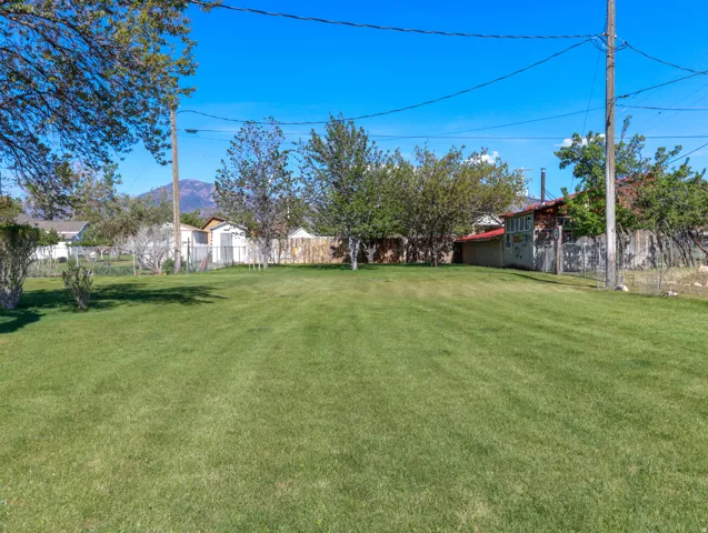 Expansive green lawn with mature trees and a distant mountain backdrop