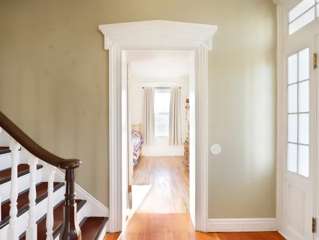 Hardwood flooring extends throughout this interior space, featuring a decorative door frame with molding