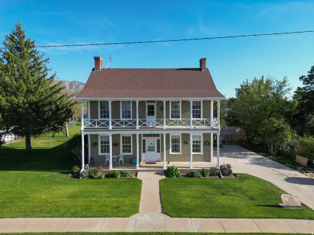 Two-story residence featuring a covered front porch and an upper-level balcony with white railings