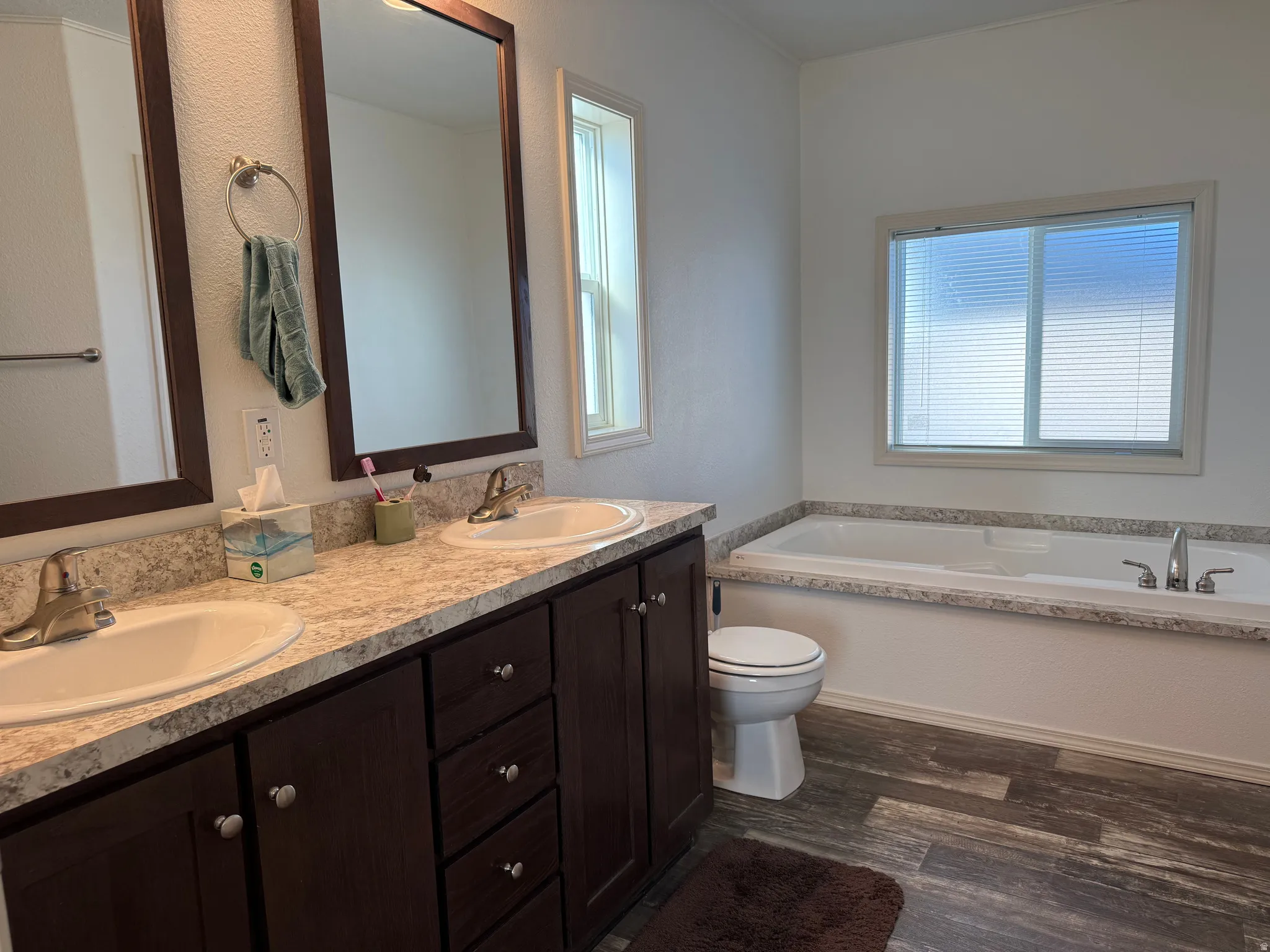 Full bath with a bath, double vanity, and dark wood-style floors