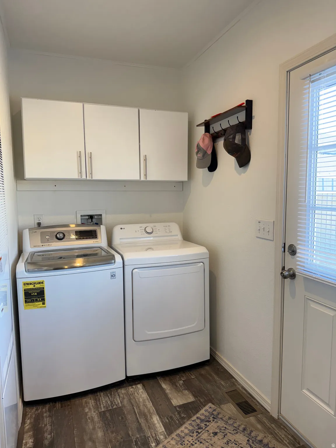 Washroom with washer and clothes dryer, cabinet space, and dark wood-type flooring