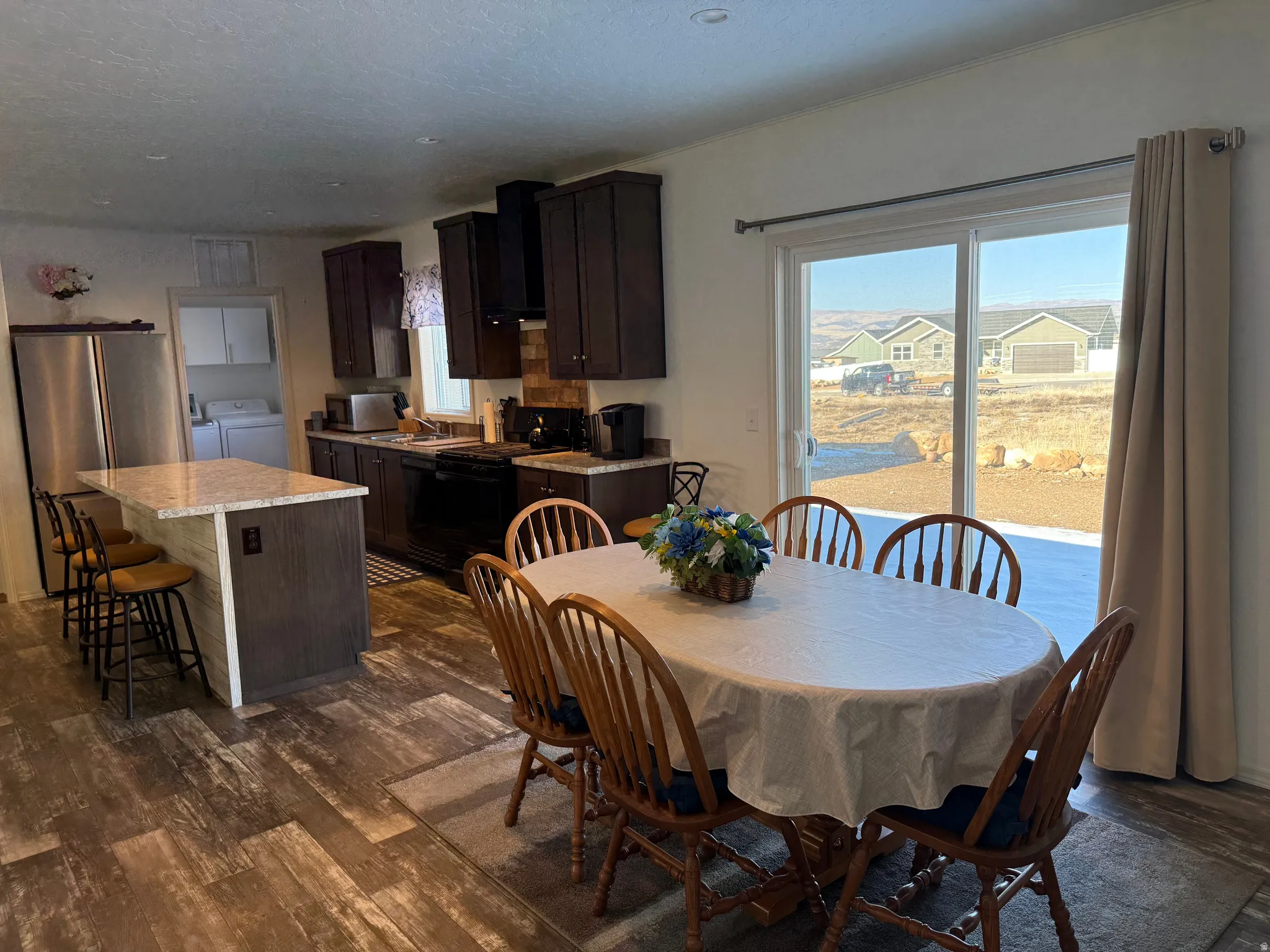 Dining space with plenty of natural light, dark wood-type flooring, independent washer and dryer, and a textured ceiling