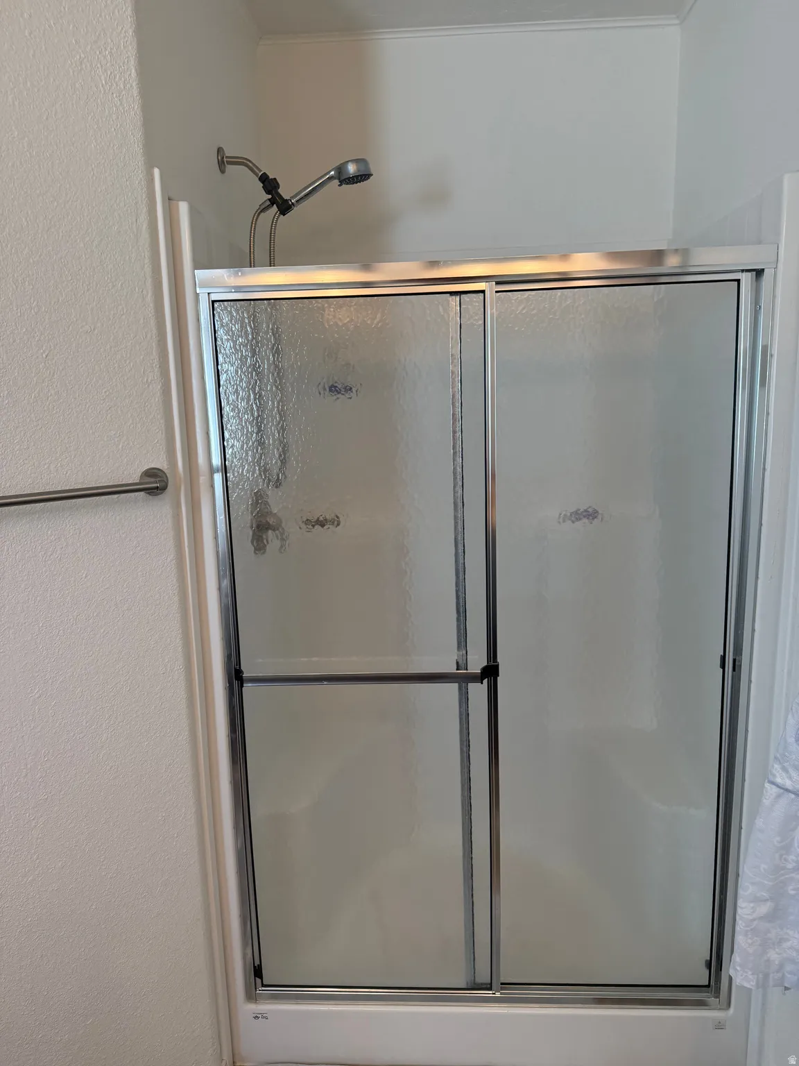 Bathroom with a shower stall and a textured wall