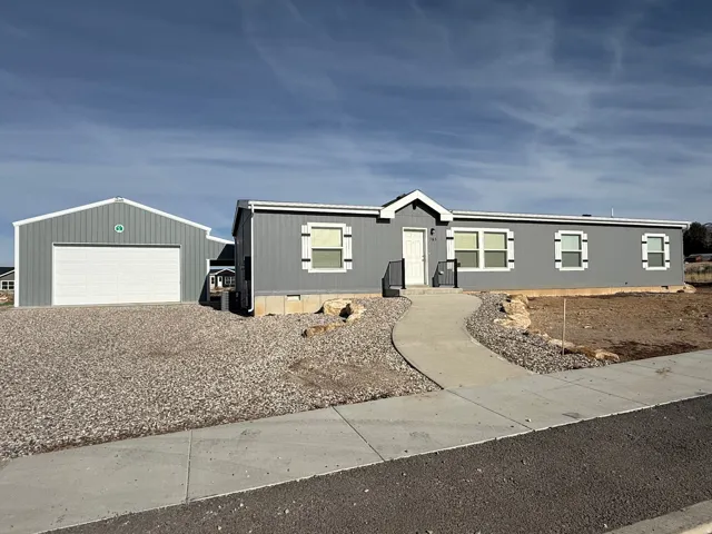 Manufactured / mobile home with a garage, an outdoor structure, and driveway