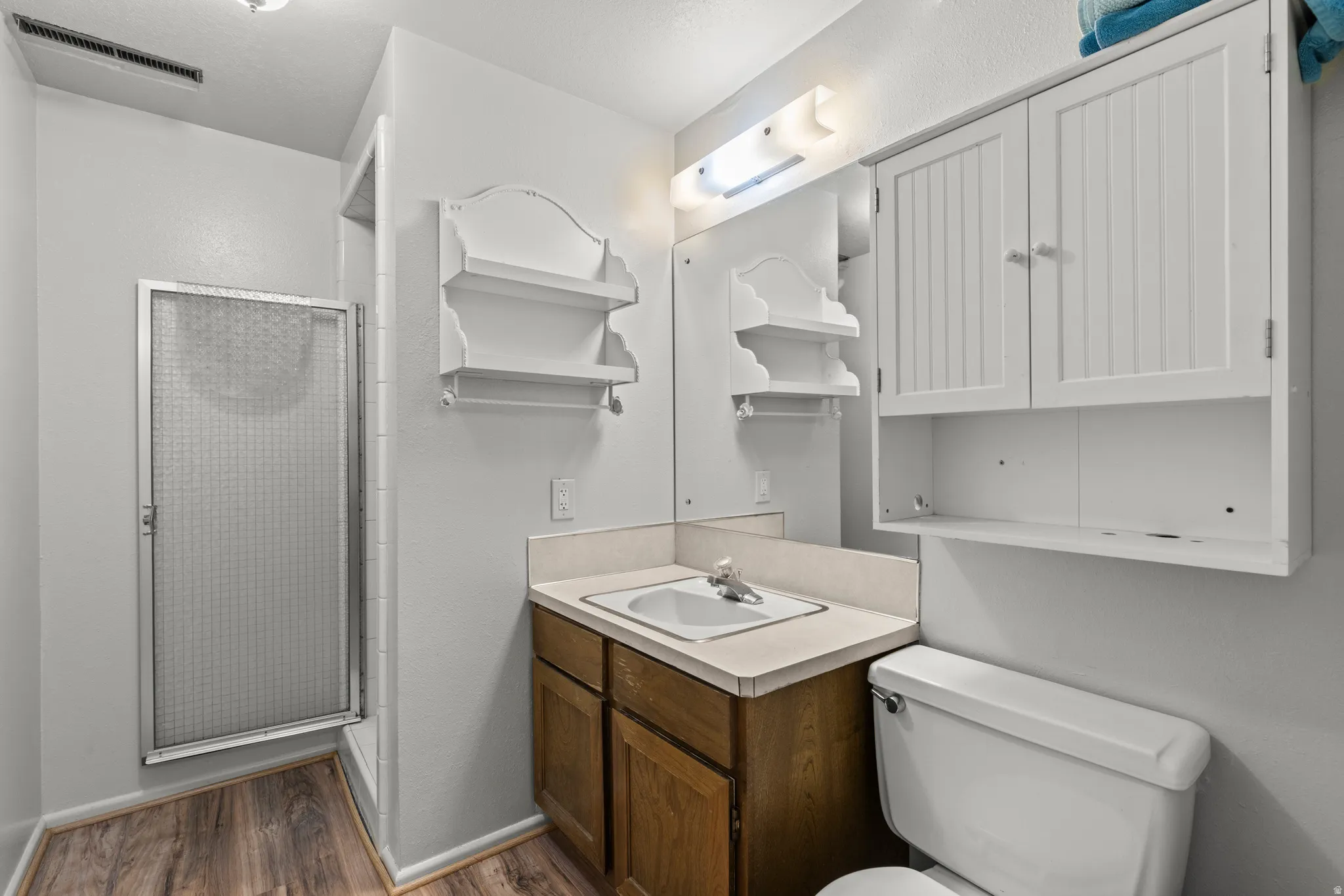 Bathroom with a stall shower, vanity, and dark wood-style floors