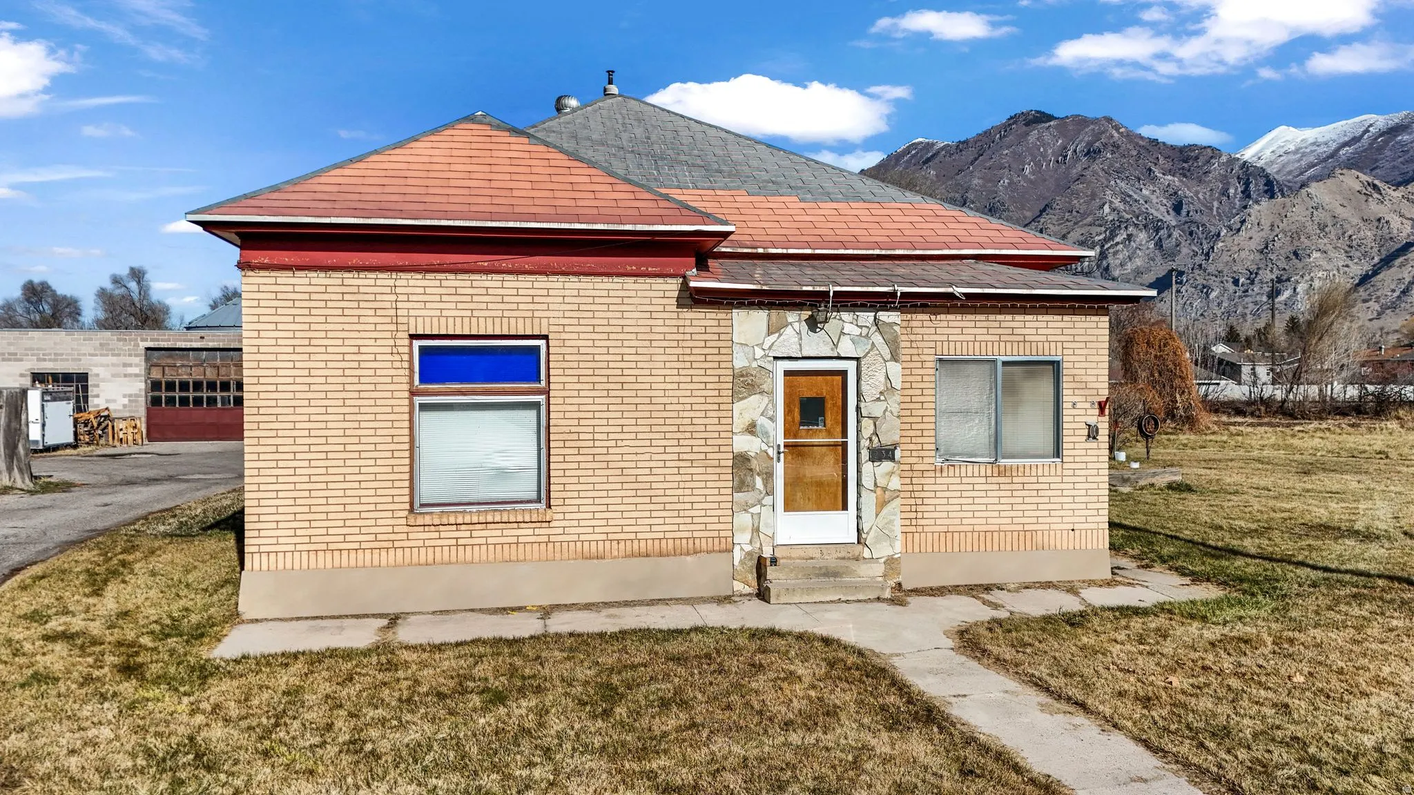 View of front facade featuring brick siding, a front lawn, entry steps, and a mountain view