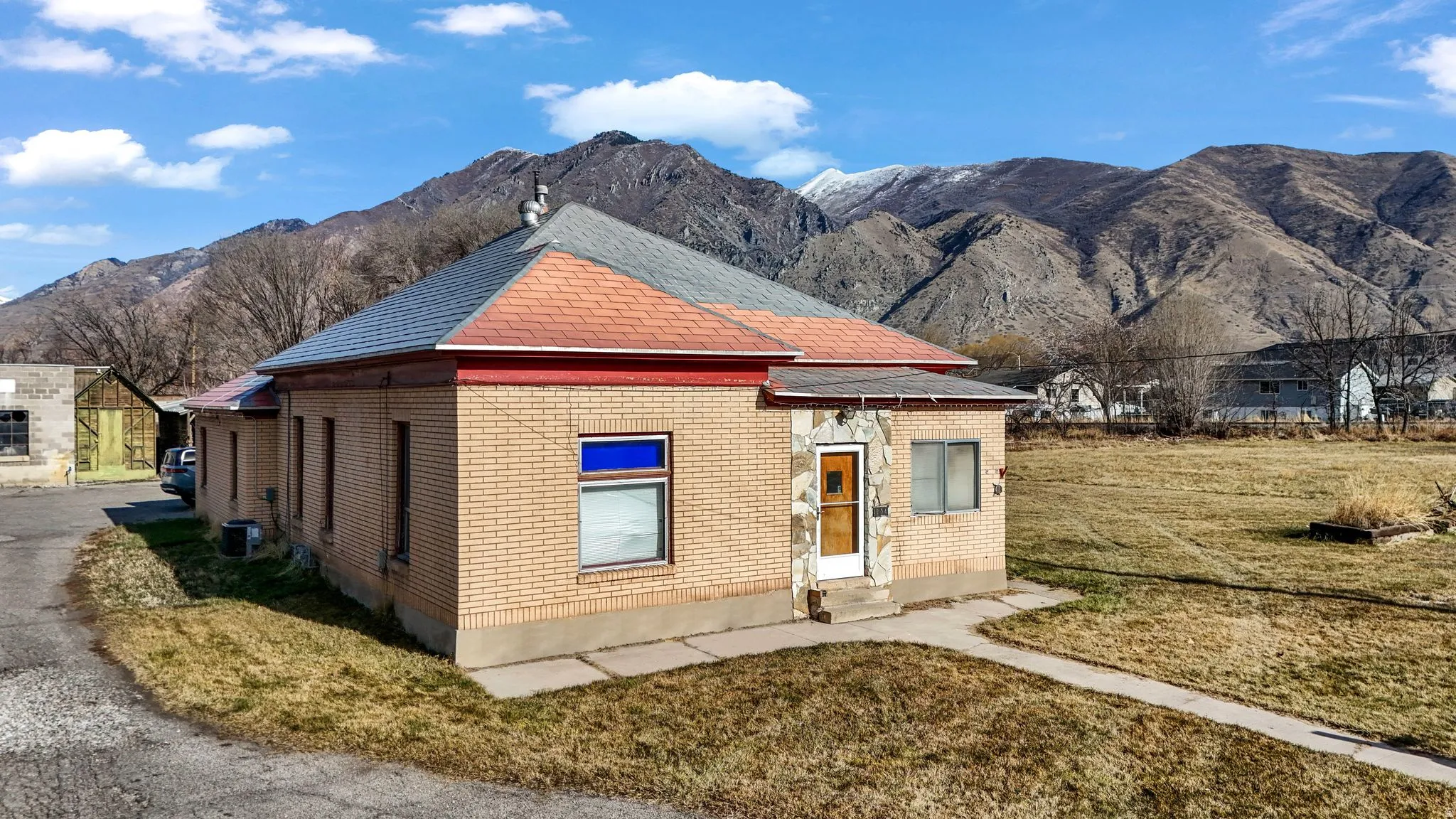 View of front of home with a mountain view, brick siding, and a front lawn