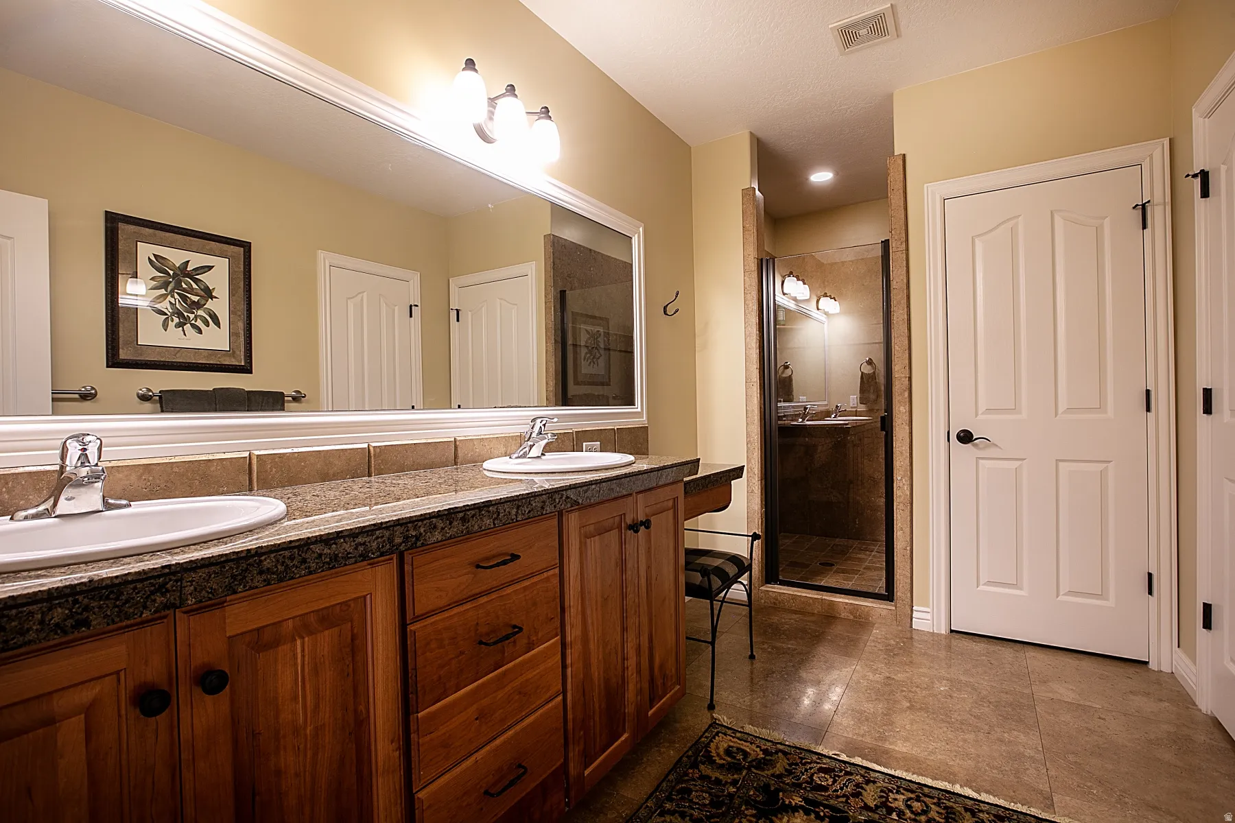 Full bath with double vanity and a stall shower