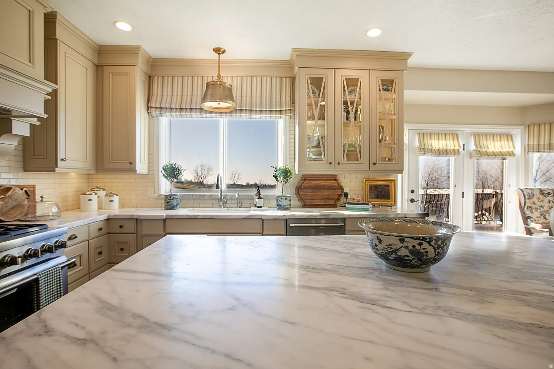 Kitchen featuring pendant lighting, light stone counters, tasteful backsplash, cream cabinetry, and recessed lighting