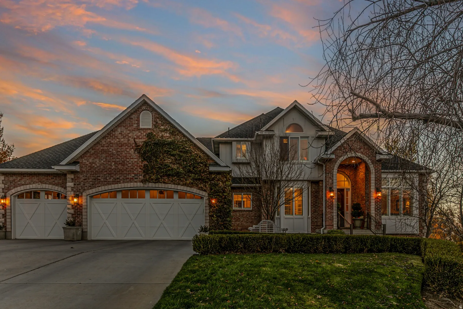Brick, Hardie Board Exterior with sidewalk lined with boxwoods and ivy growing over garage.