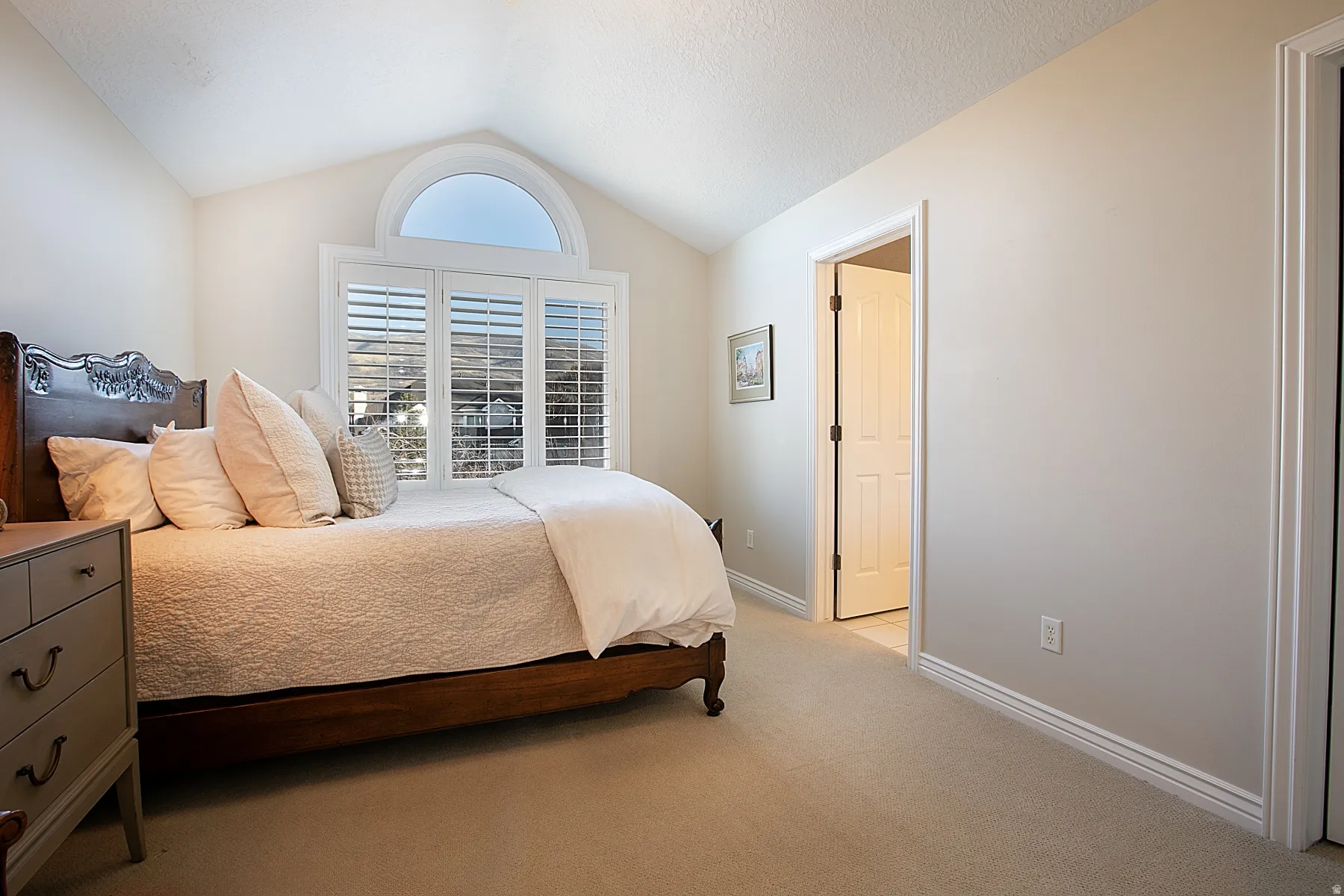 Bedroom featuring light colored carpet and vaulted ceiling