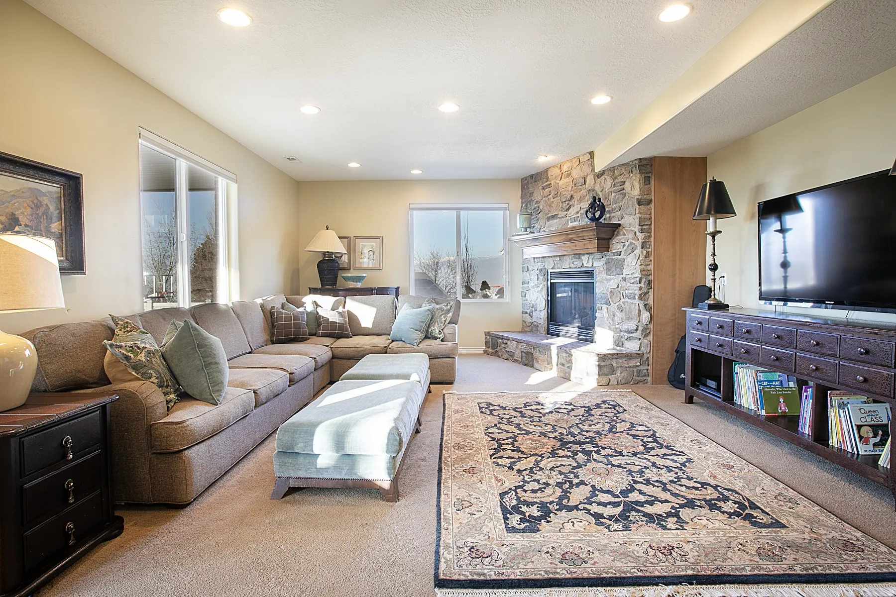 Living area featuring light carpet, a stone fireplace, and recessed lighting