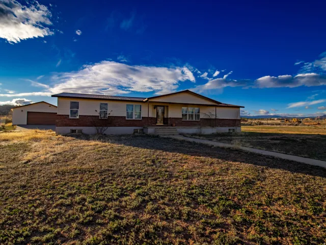 Single story home with a garage, brick siding, an outbuilding, and a front yard