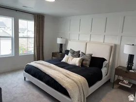 Bedroom with light carpet and a decorative wall
