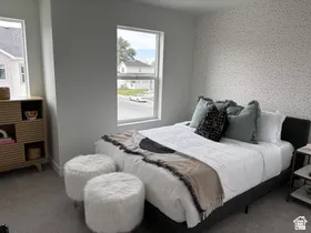 Bedroom featuring wallpapered walls, an accent wall, and carpet