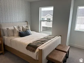 Carpeted bedroom featuring wallpapered walls and an accent wall