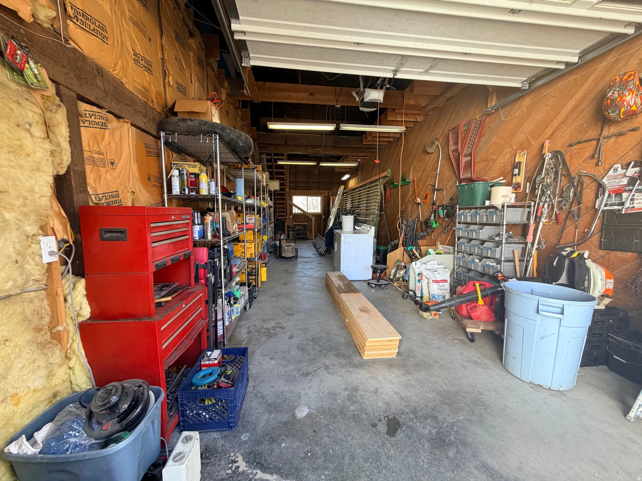 Garage with wood walls, a workshop area, washer / dryer, and a garage door opener