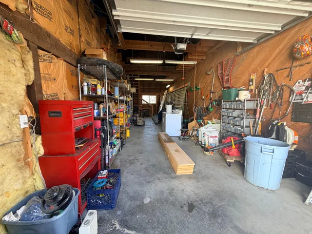 Garage with wood walls, a workshop area, washer / dryer, and a garage door opener