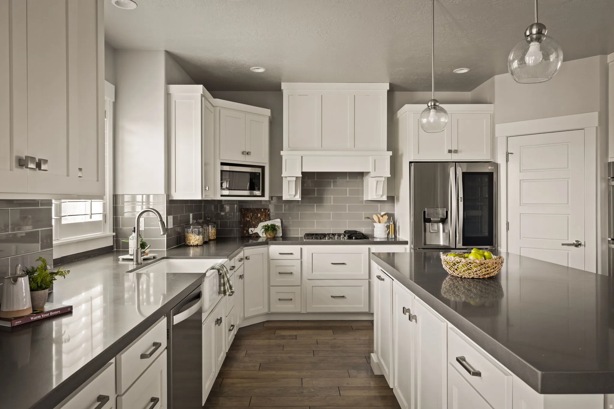 Kitchen with stainless steel appliances, pendant lighting, dark wood-style floors, white cabinetry, and backsplash