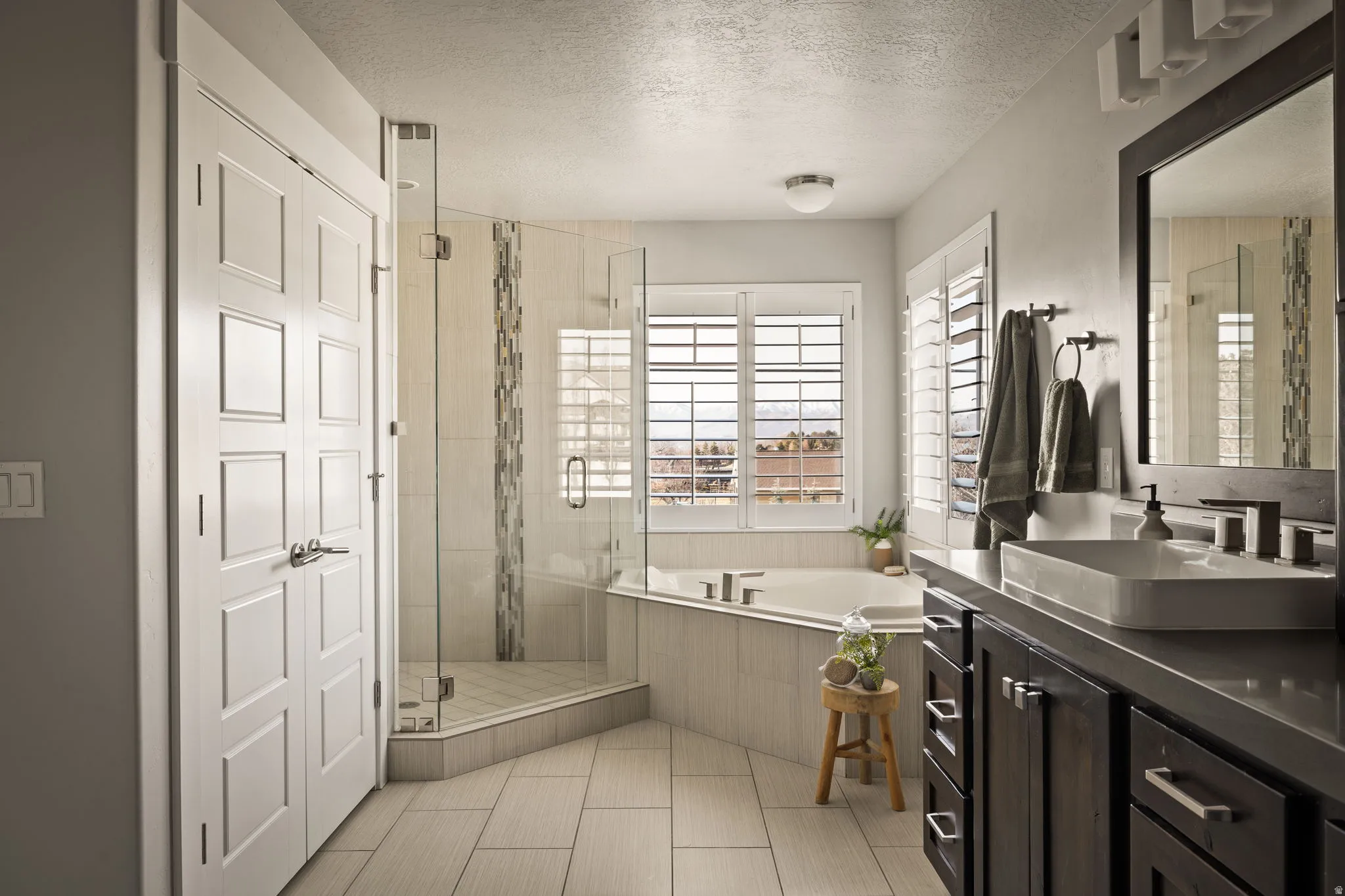 Bathroom featuring a shower stall, a textured ceiling, a garden tub, and vanity