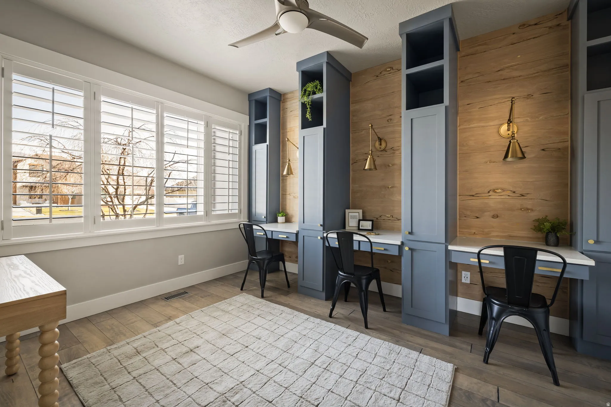 Office featuring a ceiling fan, wood finished floors, built in desk, wooden walls, and a textured ceiling