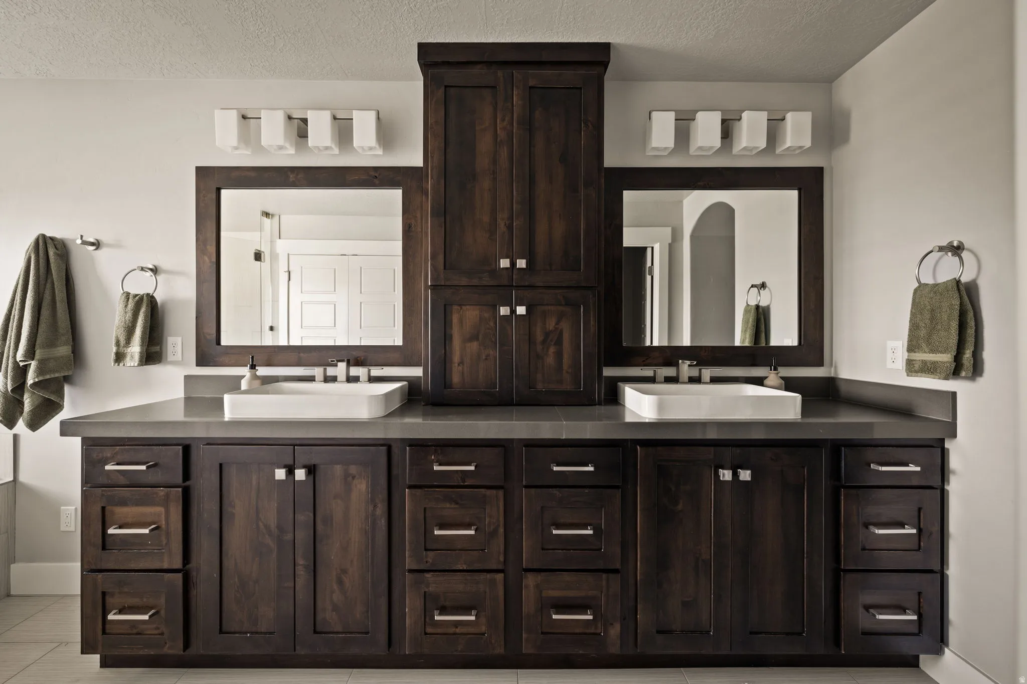 Full bathroom with double vanity, light tile patterned floors, and a textured ceiling