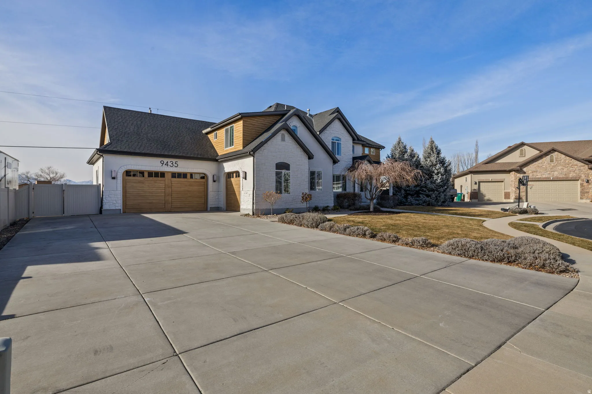 French provincial home with a shingled roof, concrete driveway, a garage, and a gate