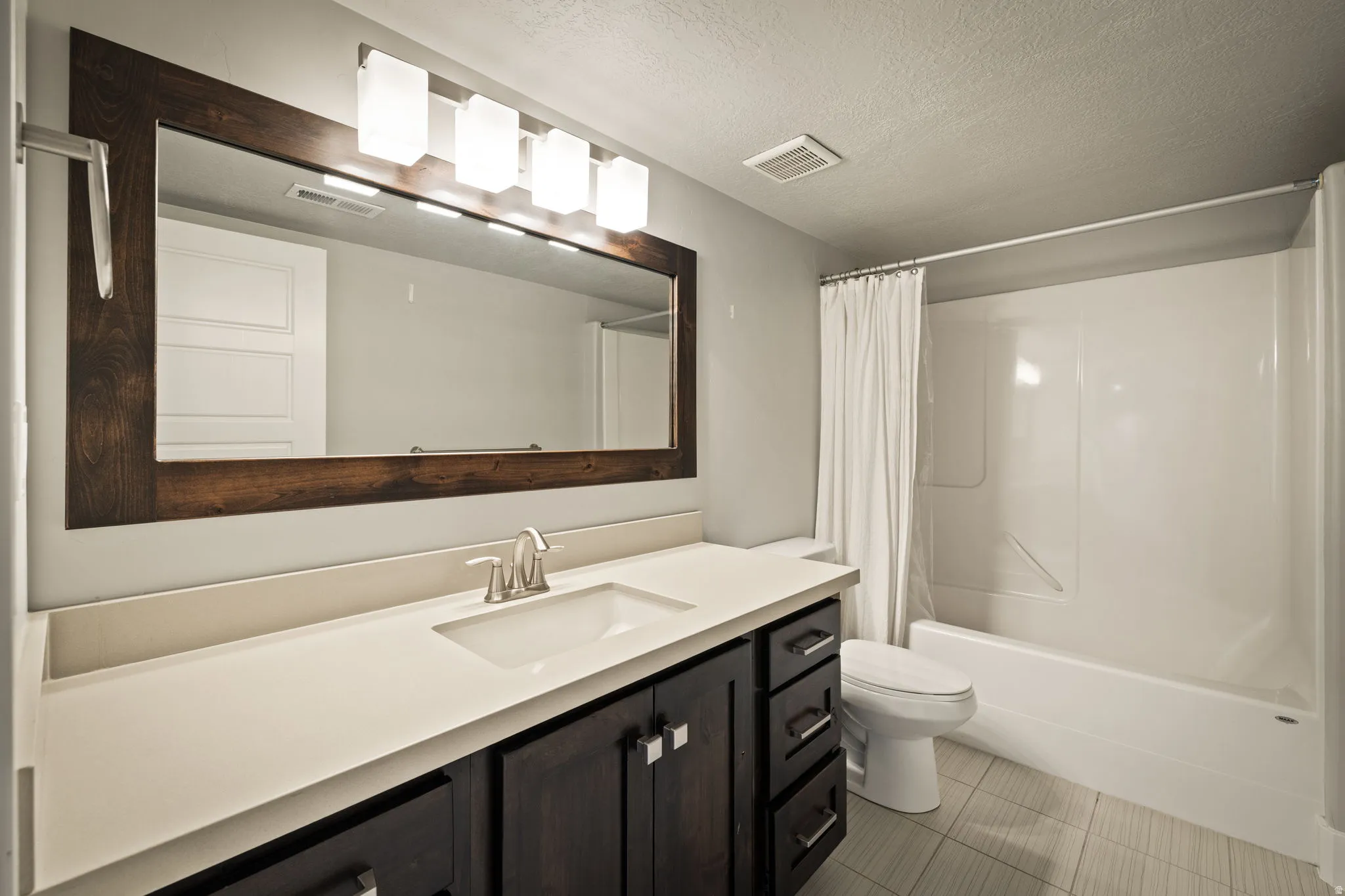 Bathroom featuring vanity, shower / tub combo, and a textured ceiling