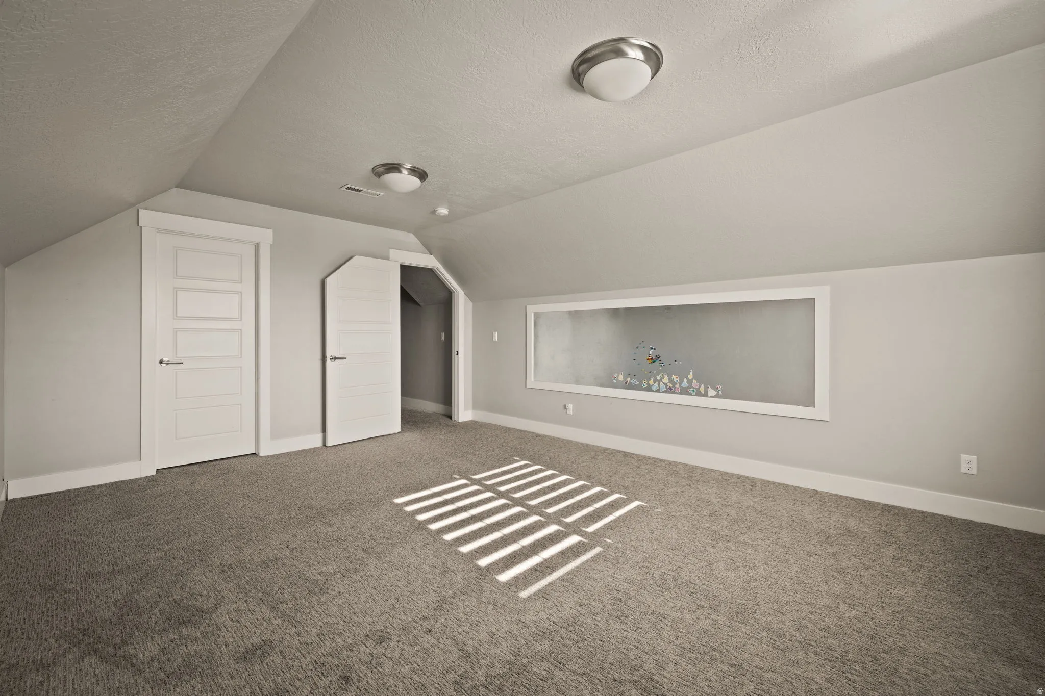 Bonus room with a textured ceiling, vaulted ceiling, and carpet