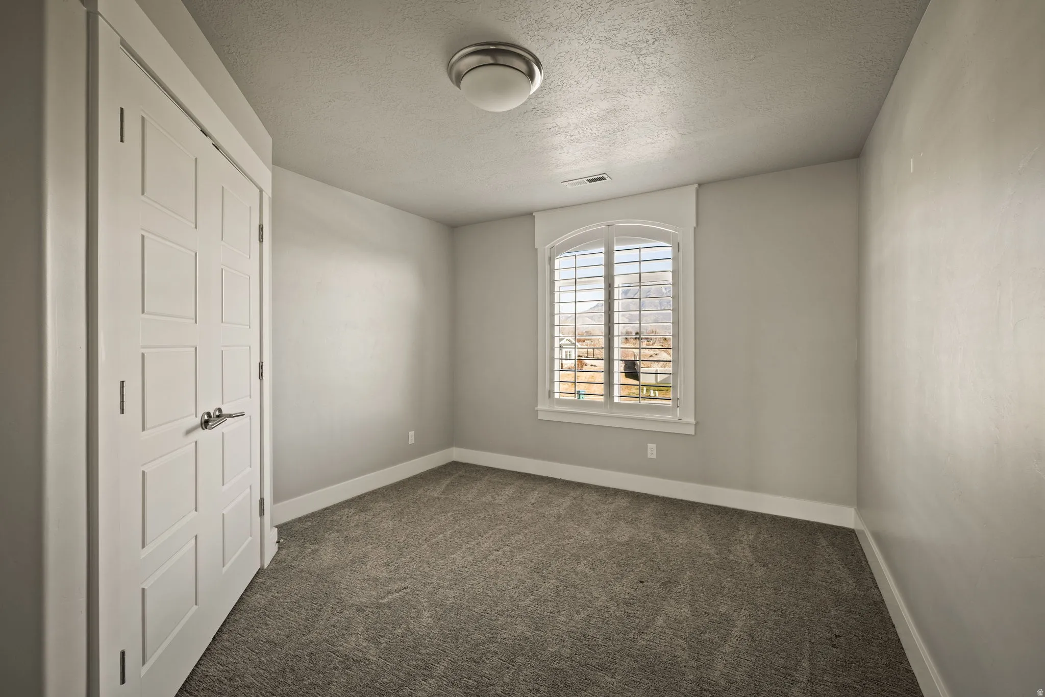 Unfurnished room with a textured ceiling and dark carpet