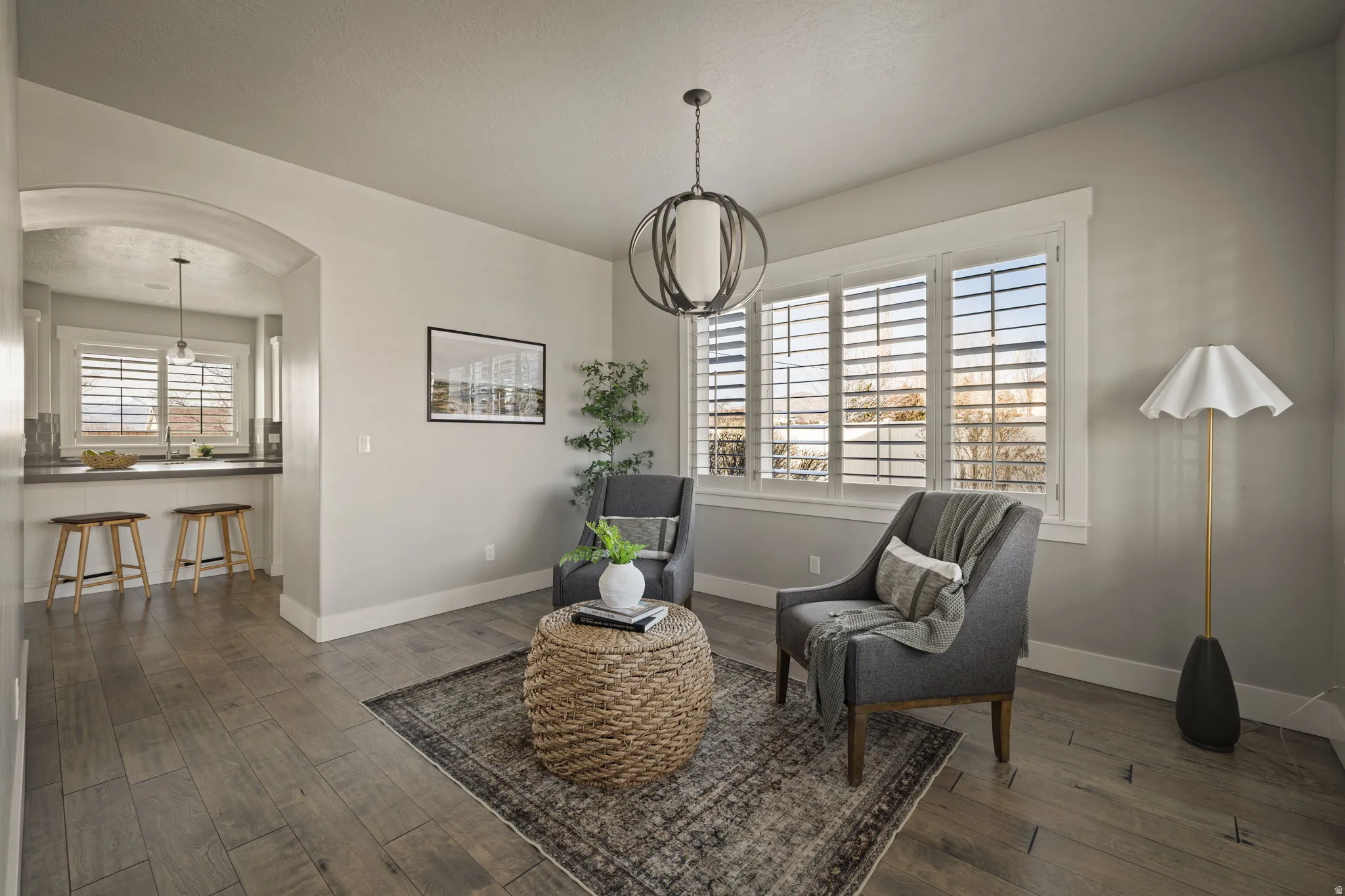 Living area with arched walkways and dark wood-style flooring