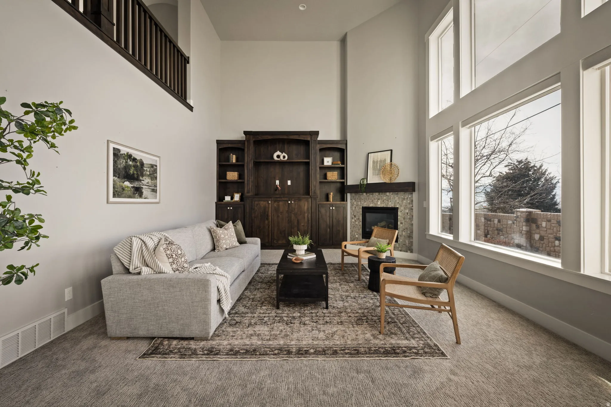 Living area with carpet flooring, a high ceiling, and a glass covered fireplace