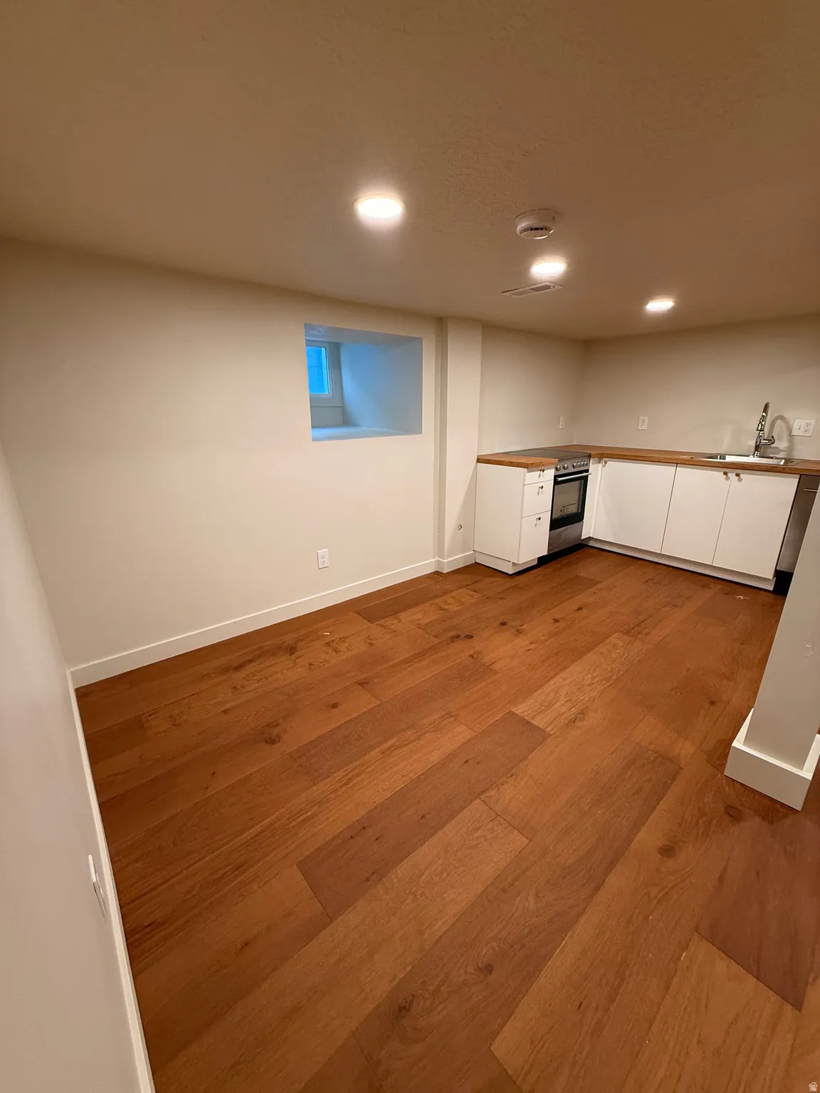 Finished below grade area with light wood-style floors and recessed lighting