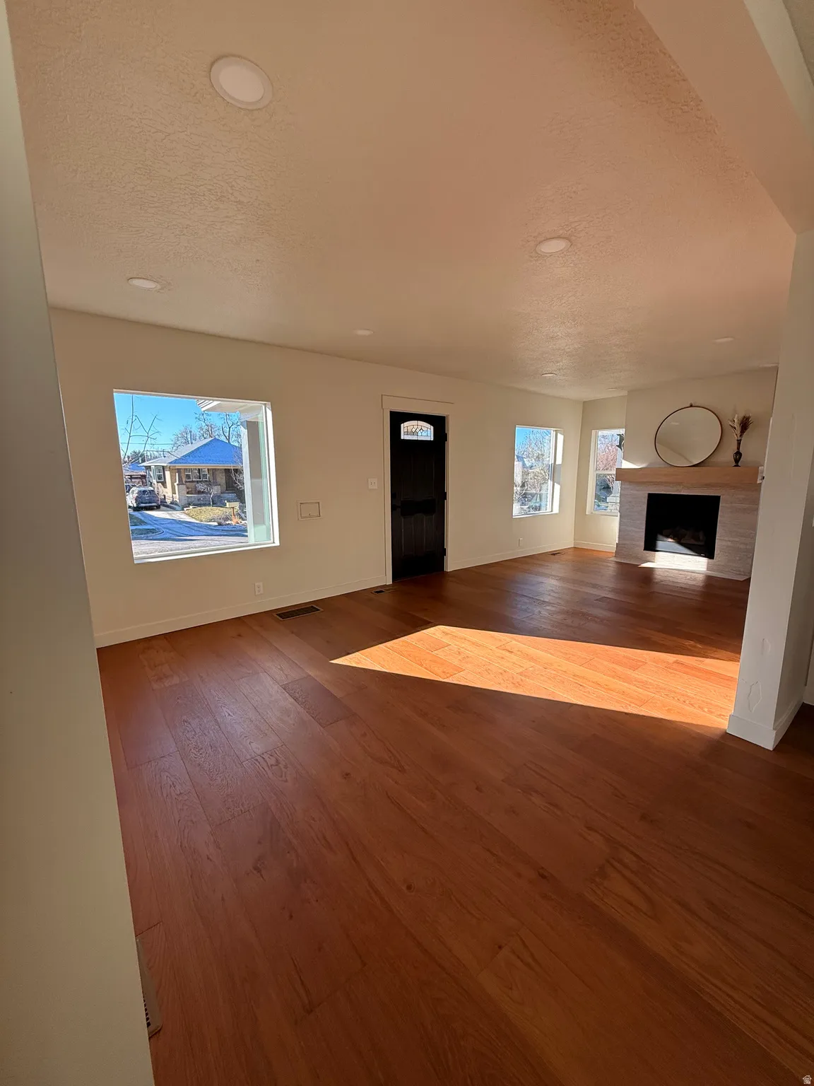 Unfurnished living room with a fireplace, dark wood-style floors, and a textured ceiling