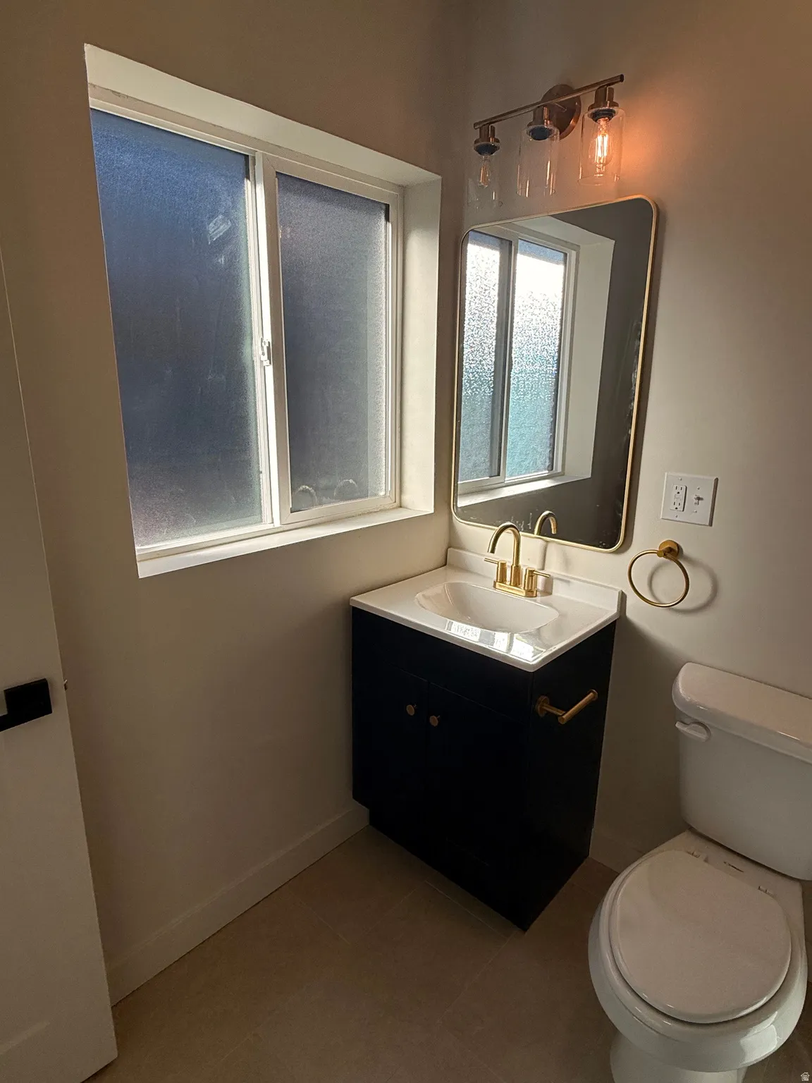 Half bathroom with vanity and dark tile patterned floors
