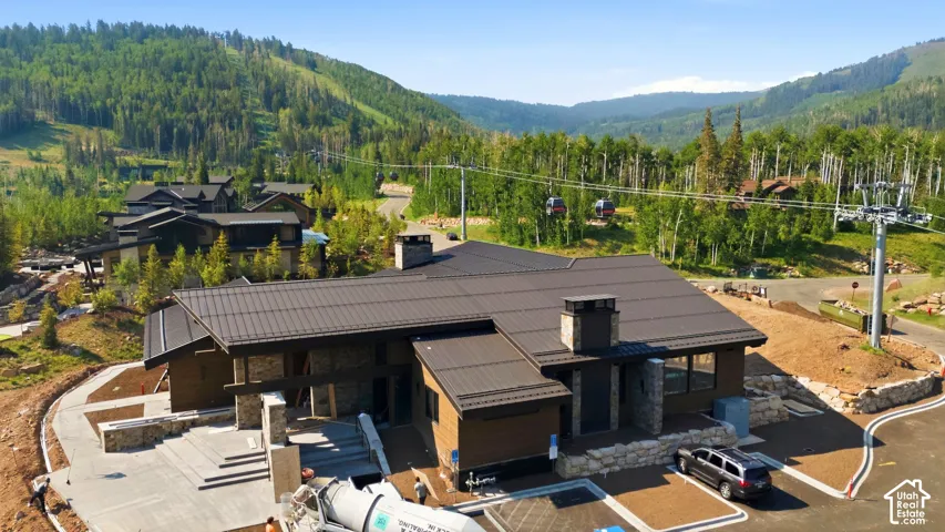 Contemporary mountain residence featuring a dark metal roof, stone accents, and expansive window placements