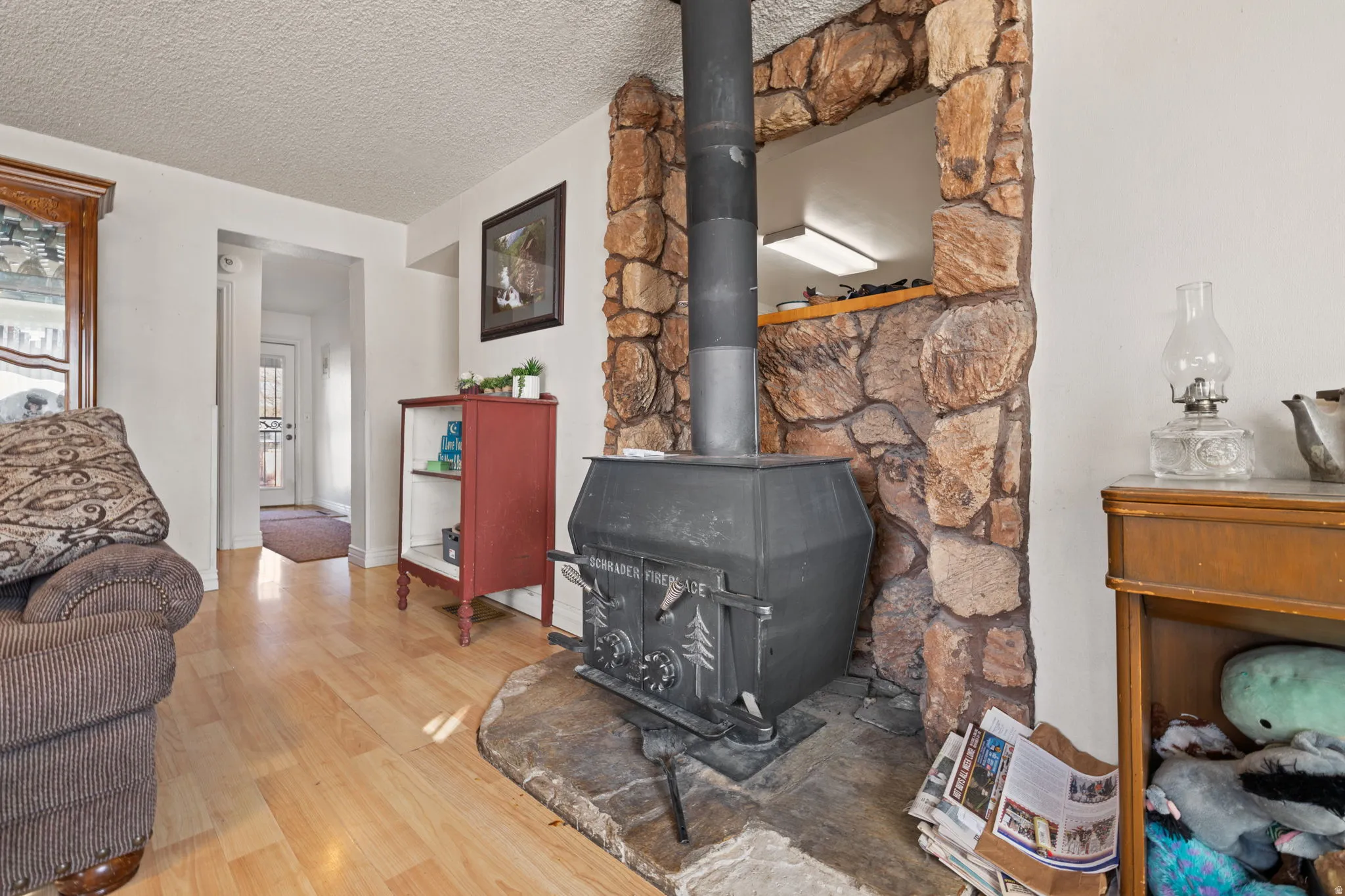 Detailed view of a wood stove, wood finished floors, and a textured ceiling