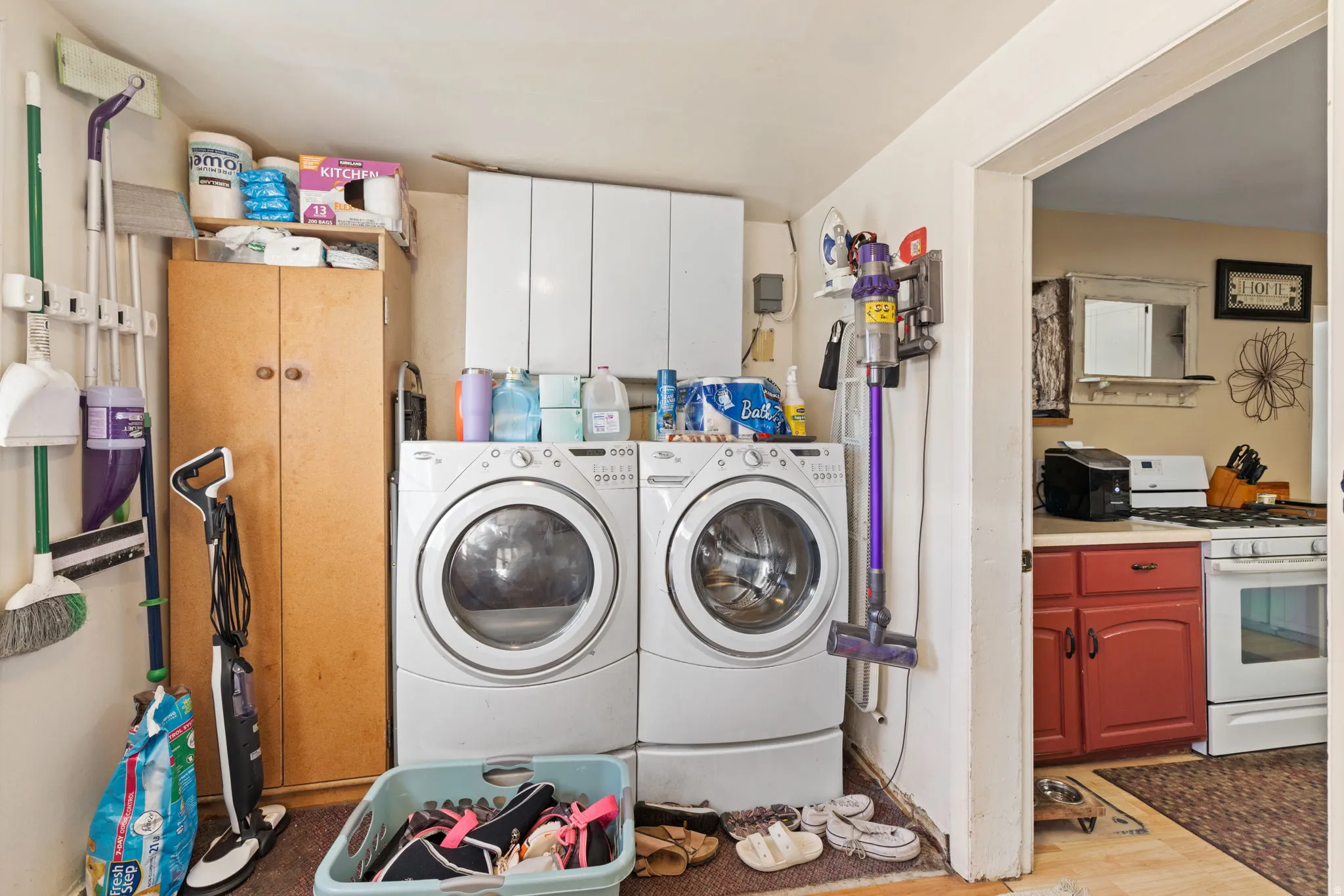 Laundry room with light wood-style floors, separate washer and dryer, and cabinet space