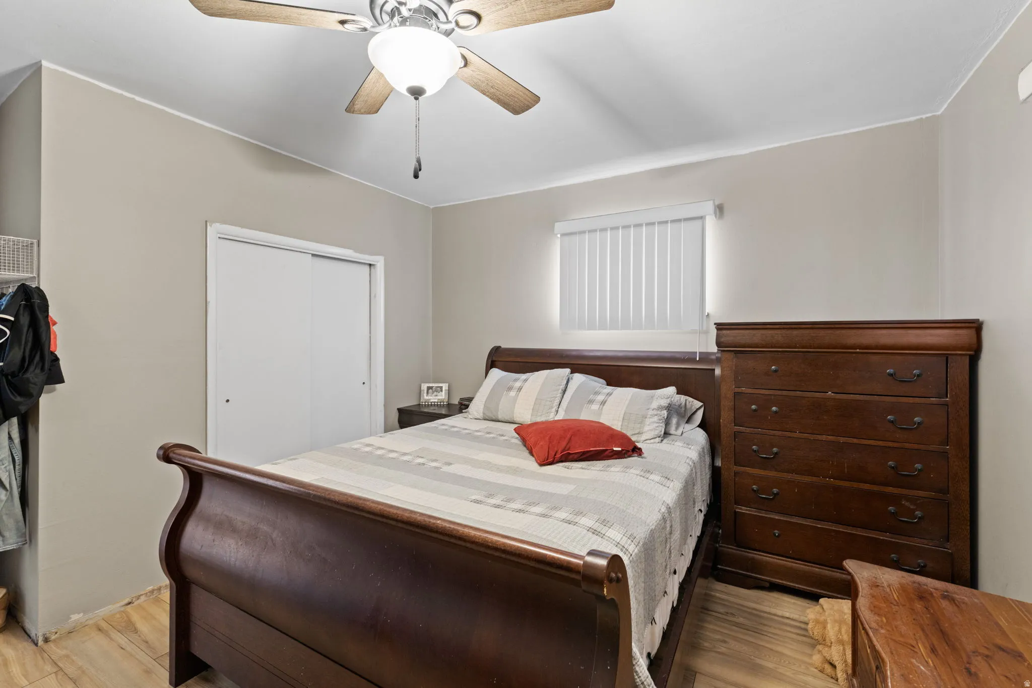 Bedroom with ceiling fan, light wood finished floors, and a closet