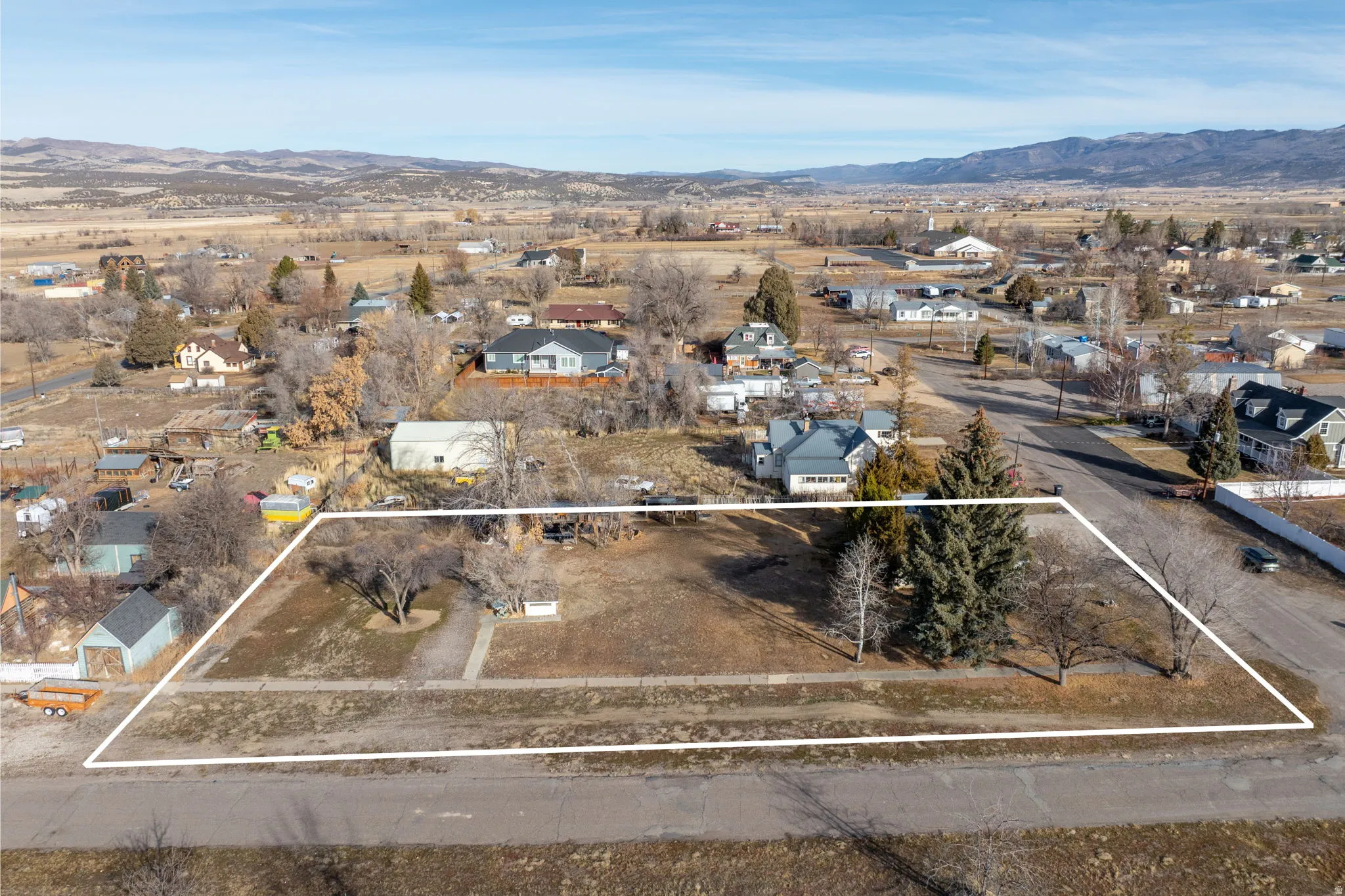 Aerial perspective of suburban area featuring a mountain backdrop and property parcel outlined