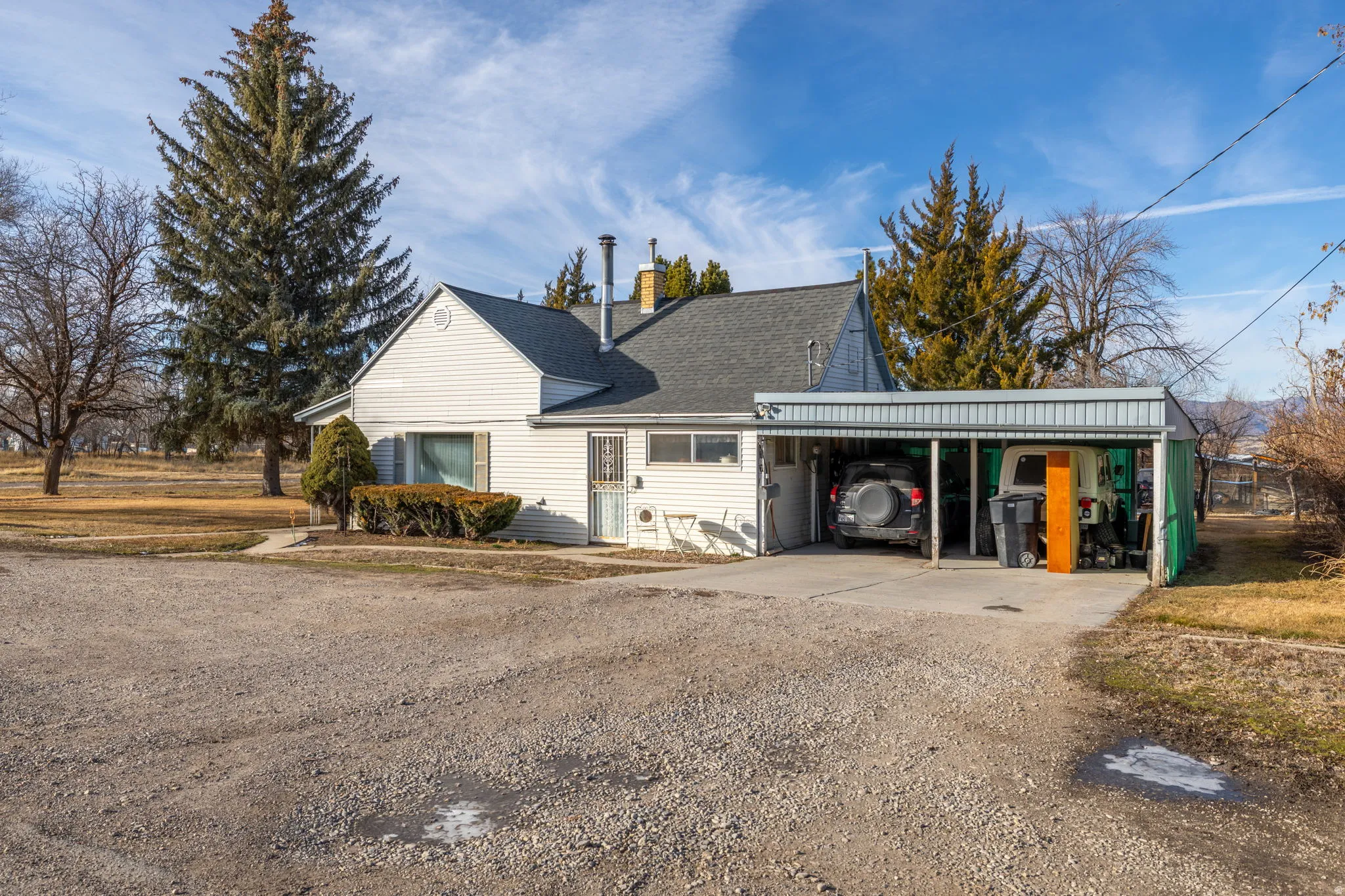 View of home's exterior with a carport, driveway, a chimney, and a shingled roof