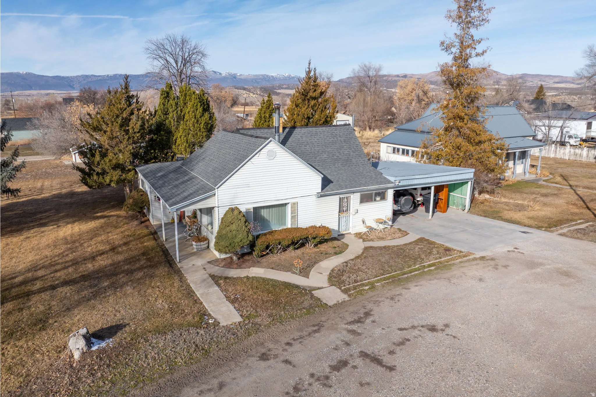 View of front of property with a carport, concrete driveway, a mountain view, and roof with shingles