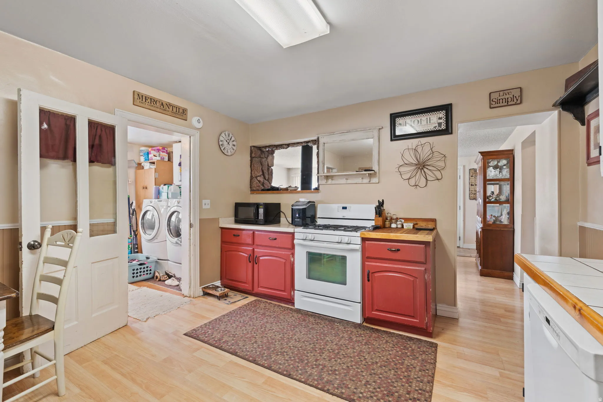 Kitchen featuring separate washer and dryer, white appliances, light wood-style floors, open shelves, and tile counters