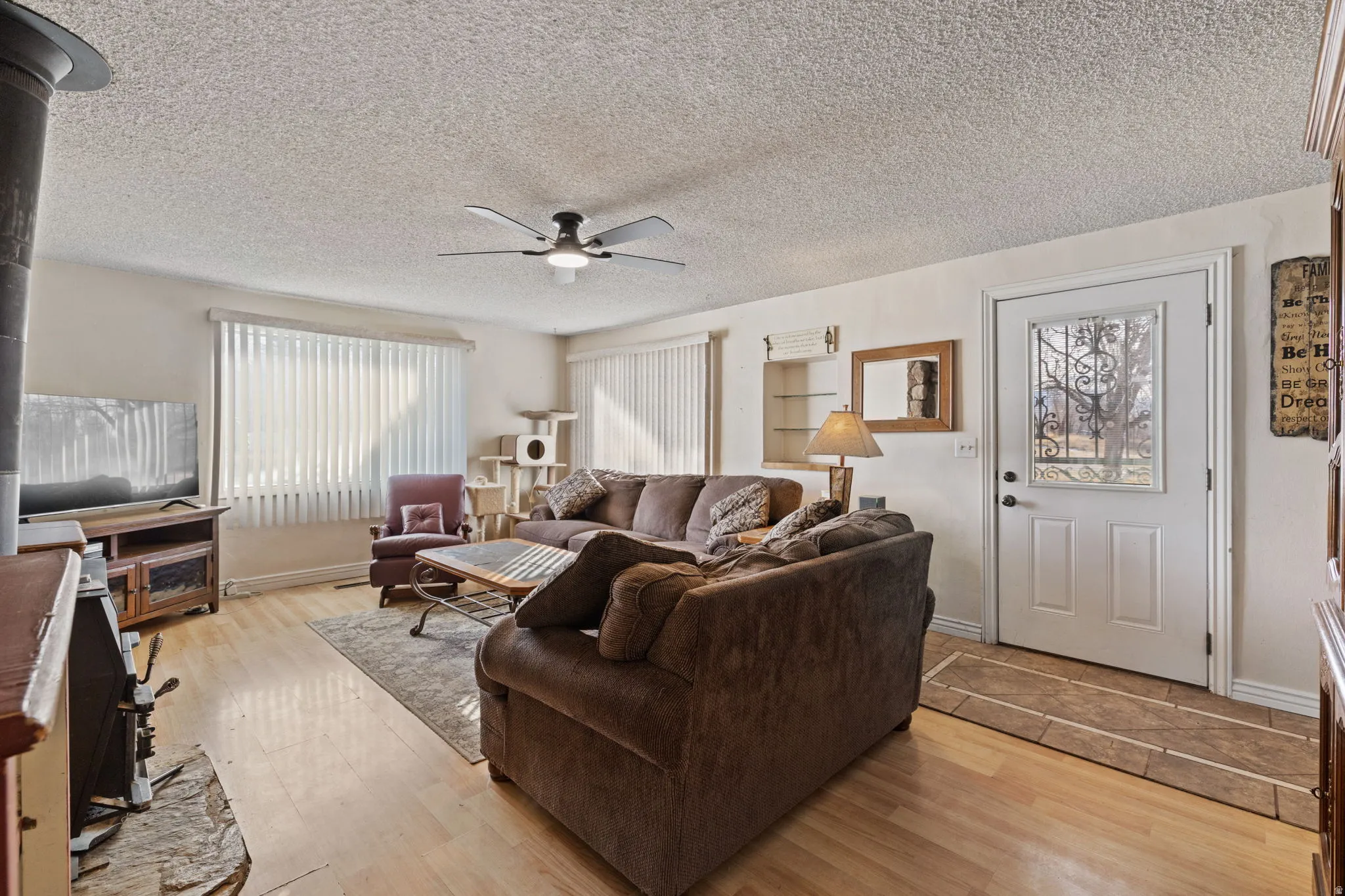 Living area featuring a ceiling fan, a textured ceiling, and light wood finished floors