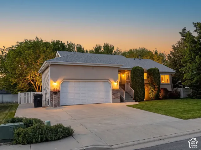 Single-story residence featuring a two-car garage, stone veneer accents, concrete driveway, and manicured lawn