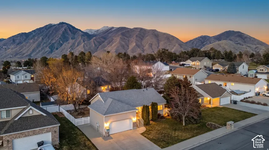 Single-story residence featuring a two-car garage, concrete driveway, asphalt shingle roof, and white vinyl perimeter fencing