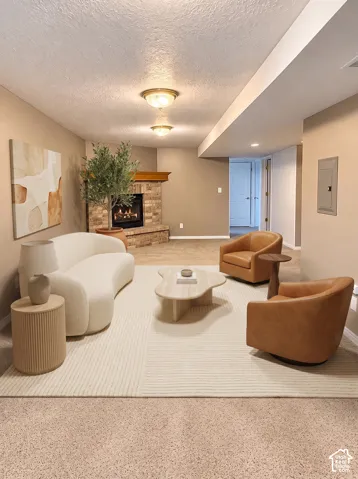 Corner fireplace featuring a masonry surround, brick hearth, and decorative wood mantel, complemented by dual flush-mount ceiling light fixtures and neutral carpeting