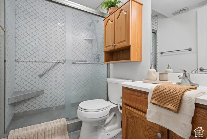 Walk-in shower featuring lantern-pattern wall tile, built-in corner bench, and sliding glass enclosure, accented by a wood cabinetry vanity and overhead storage unit