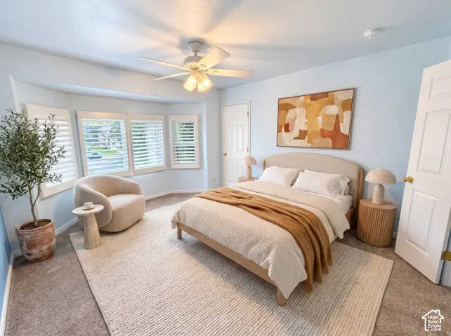 Bay window featuring plantation shutters, neutral wall color, and a ceiling-mounted light fixture with integrated fan
